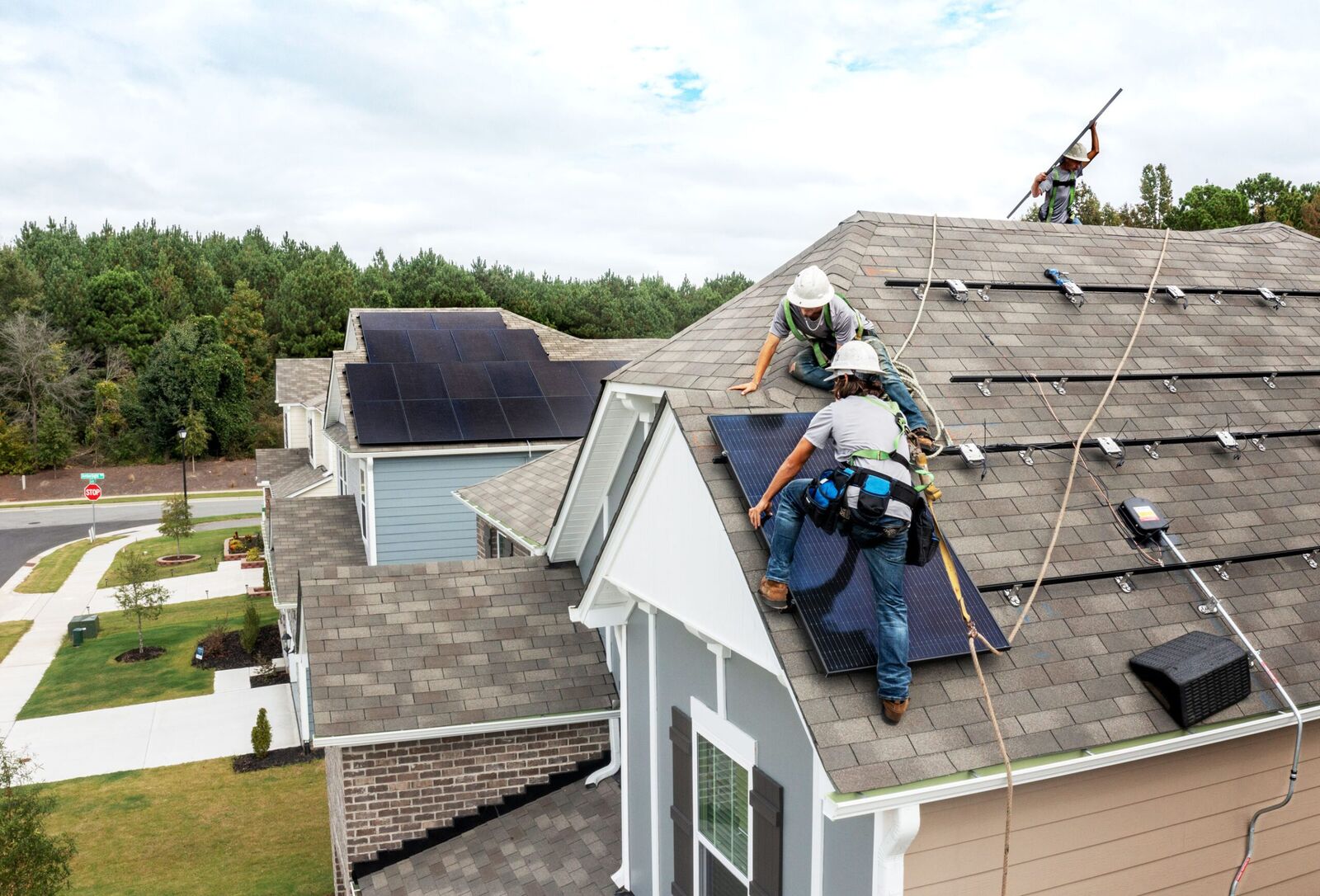Installation crew mounting all-black solar panels on a residential roof